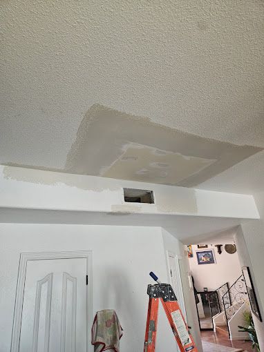 A room with a ladder and a hole in the ceiling.