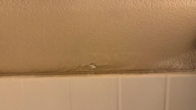 A close up of a bathroom wall with a hole in it.