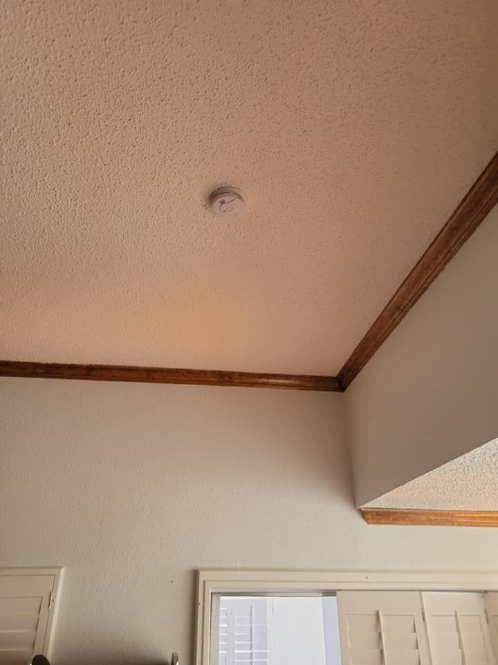 There is a smoke detector on the ceiling of the room.