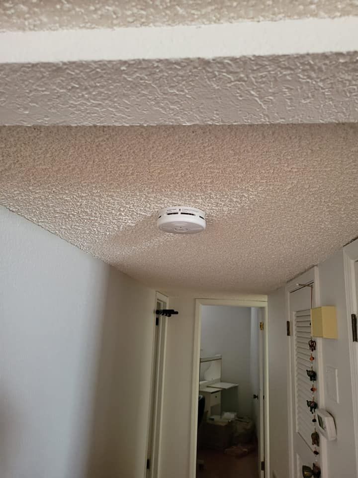 A smoke detector is hanging from the ceiling of a room.