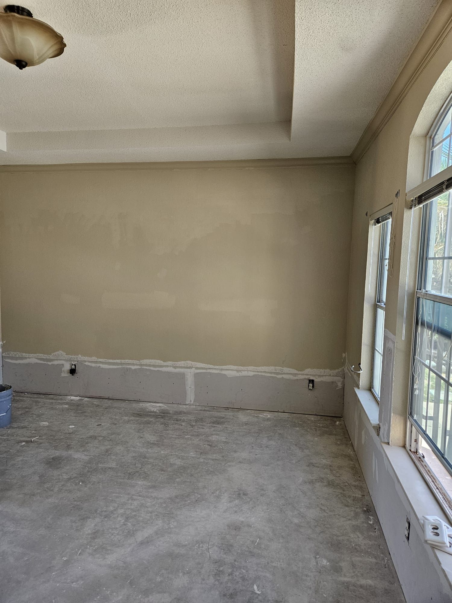 An empty room with a ceiling fan and a lot of windows.