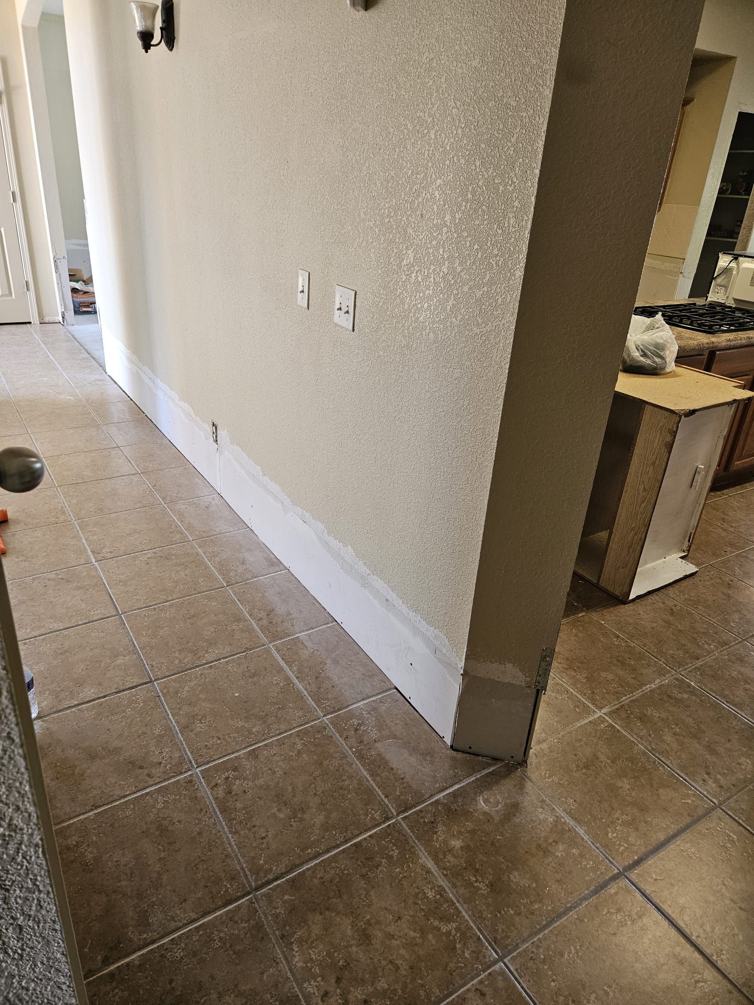 A hallway in a house with tile floors and a white wall.