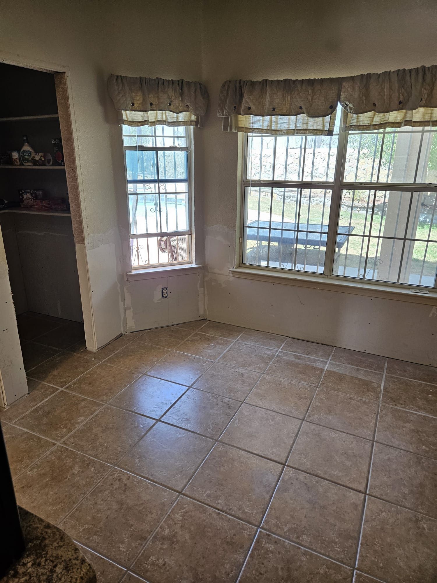 An empty room with tile floors and two windows.