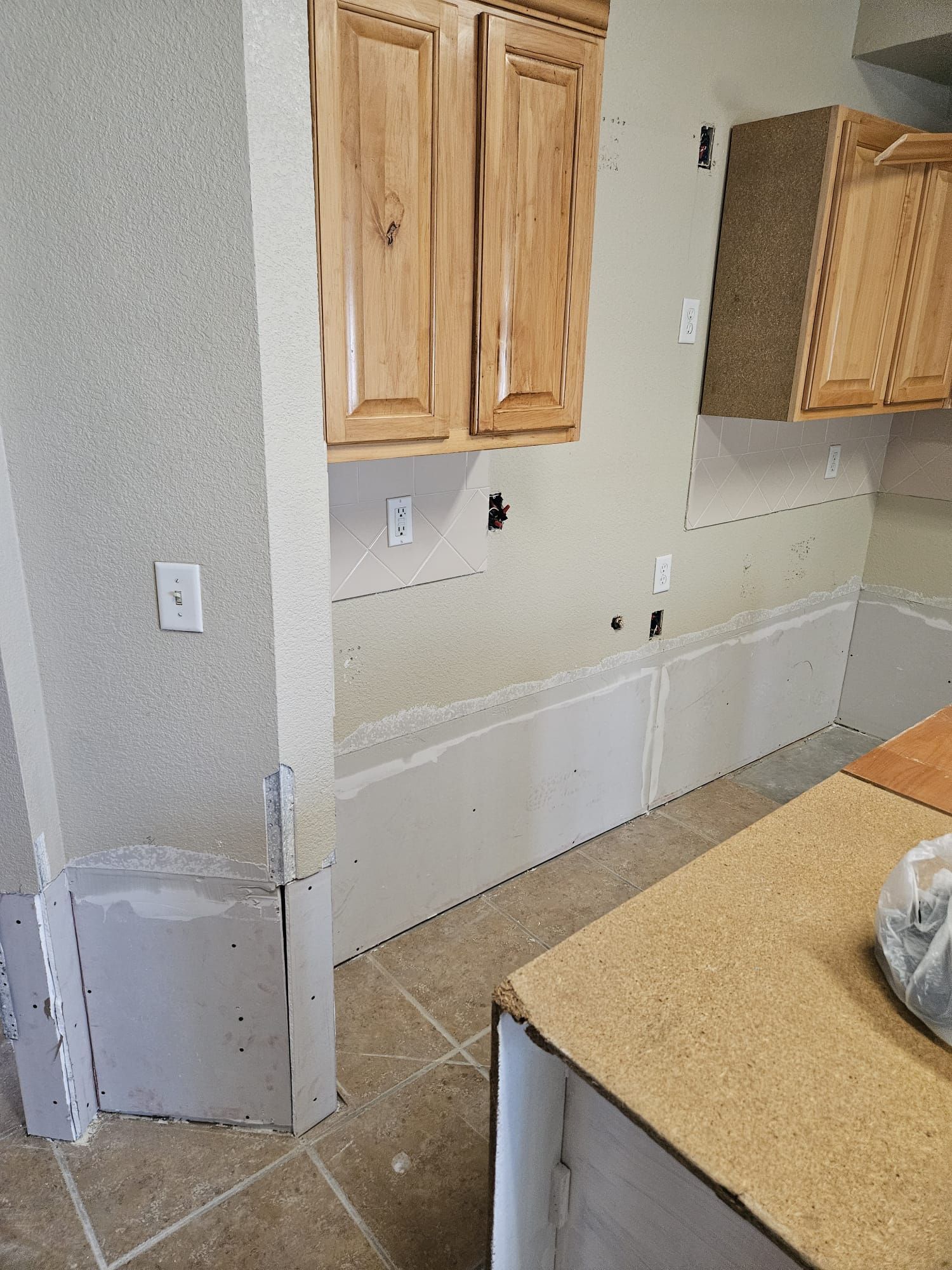 A kitchen with wooden cabinets and tile floors is being remodeled.