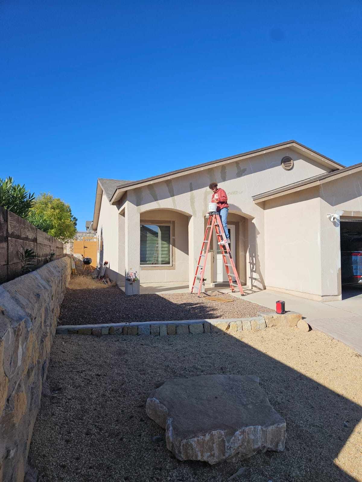 A man is standing on a ladder in front of a house.