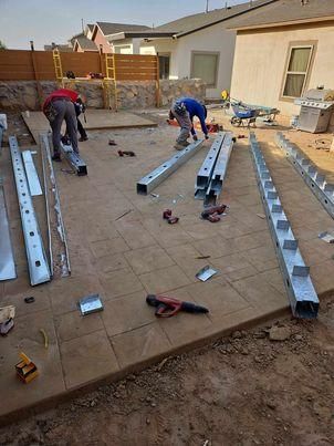 A group of men are working on a metal structure in a backyard.