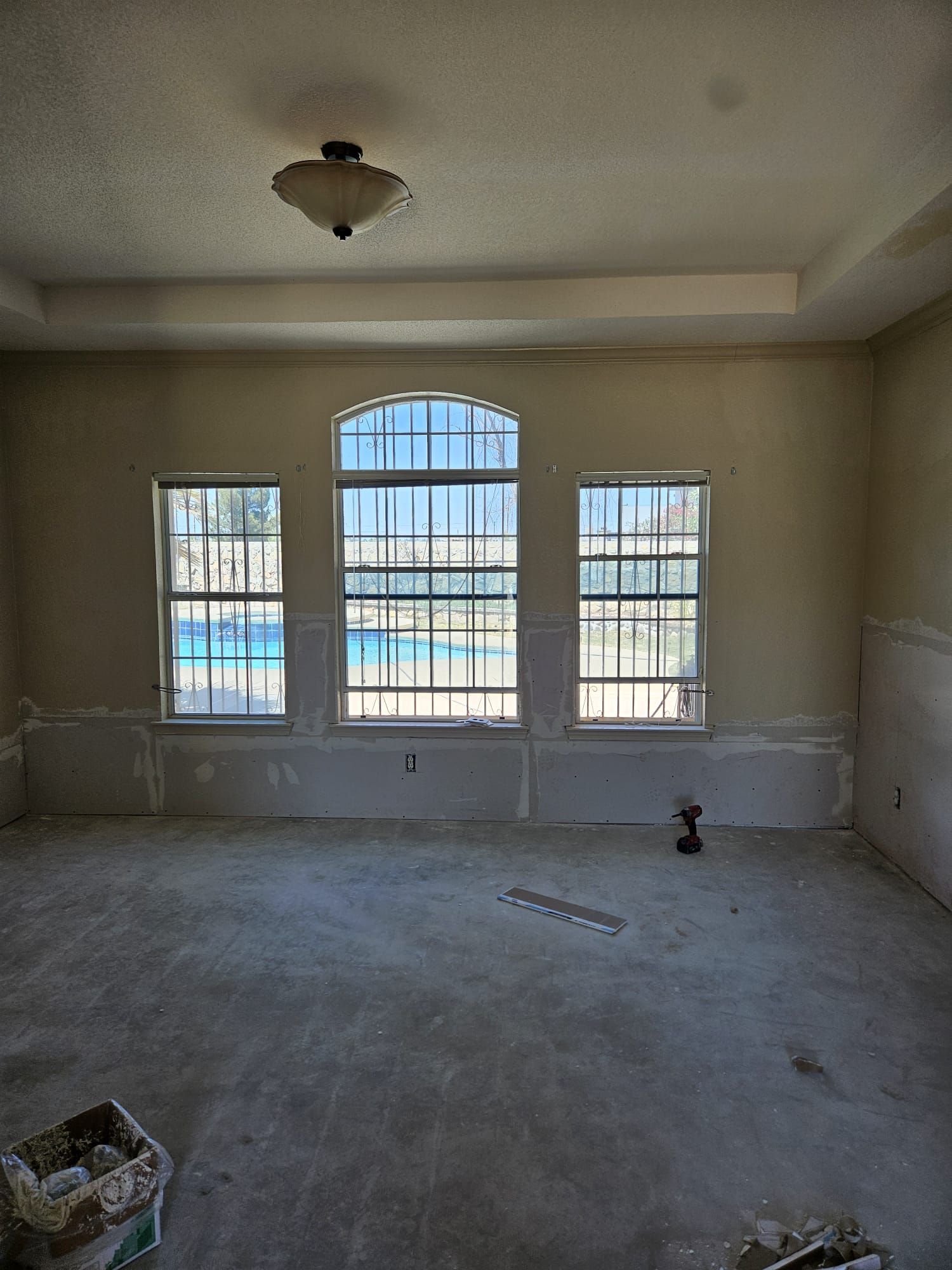 A room with a lot of windows and a pool in the background.