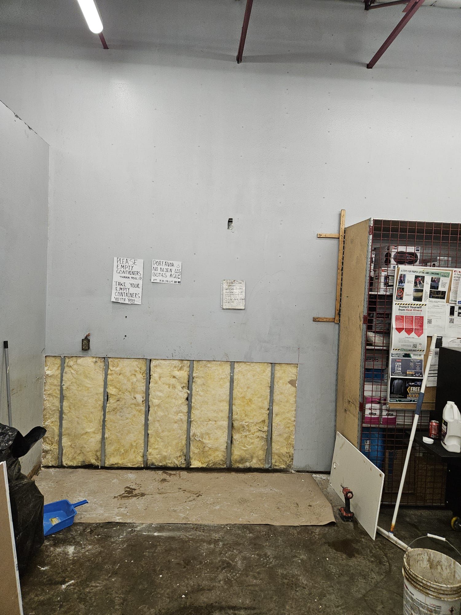 A room with a lot of insulation on the walls and a bucket on the floor.