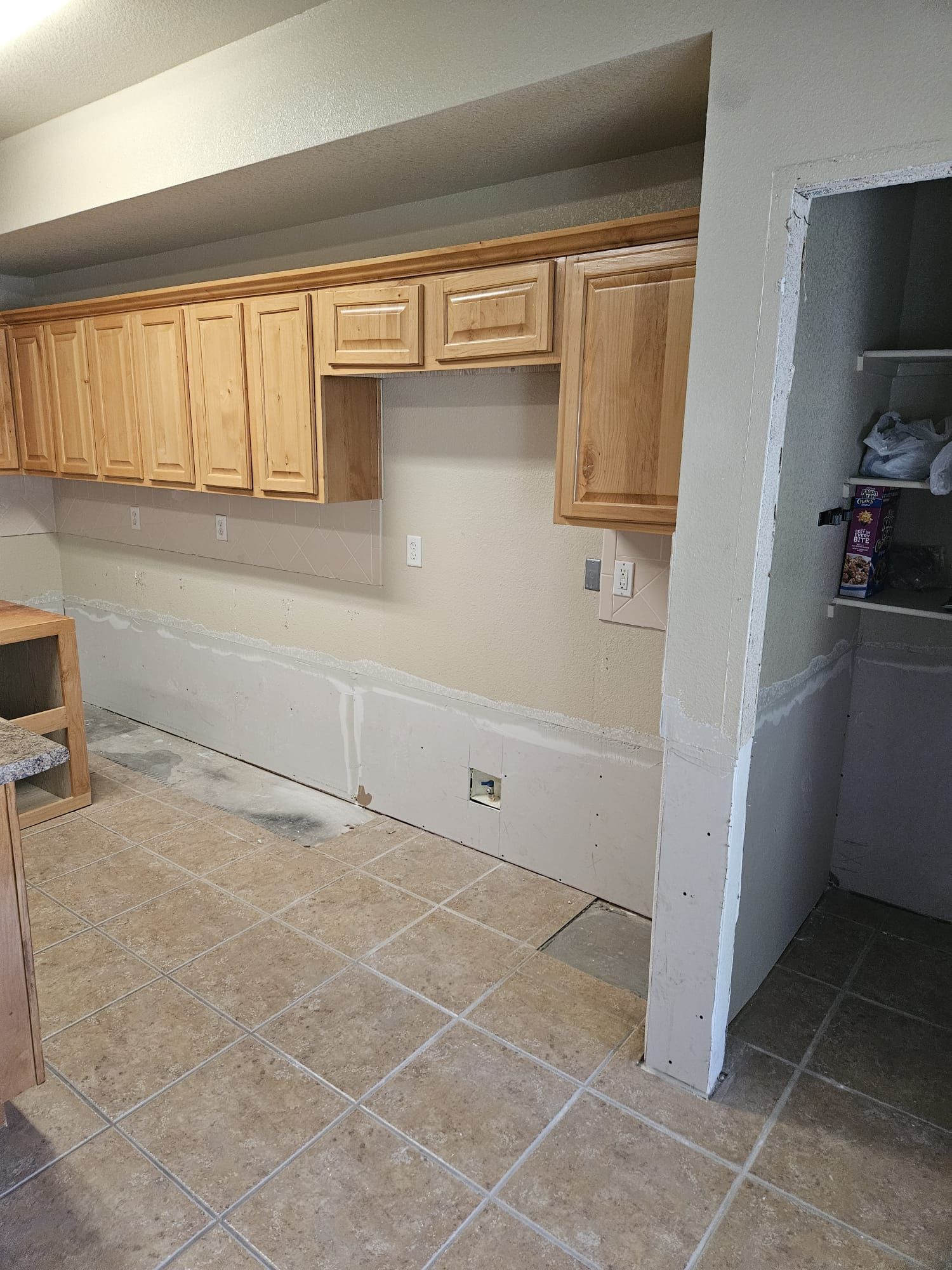 A kitchen with wooden cabinets and tile floors is being remodeled.
