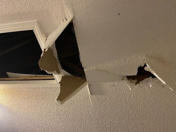 A hole in the ceiling of a room with a window.