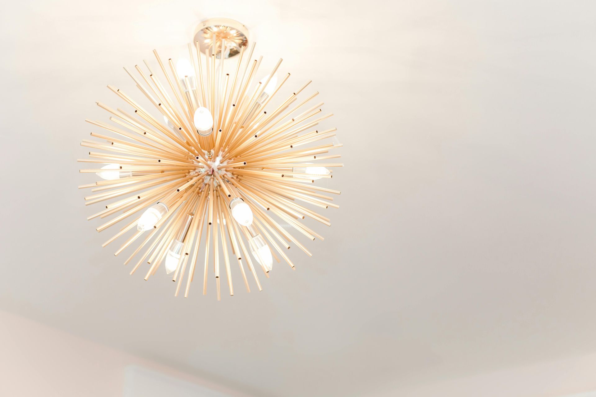 Gold sputnik chandelier against a white ceiling.