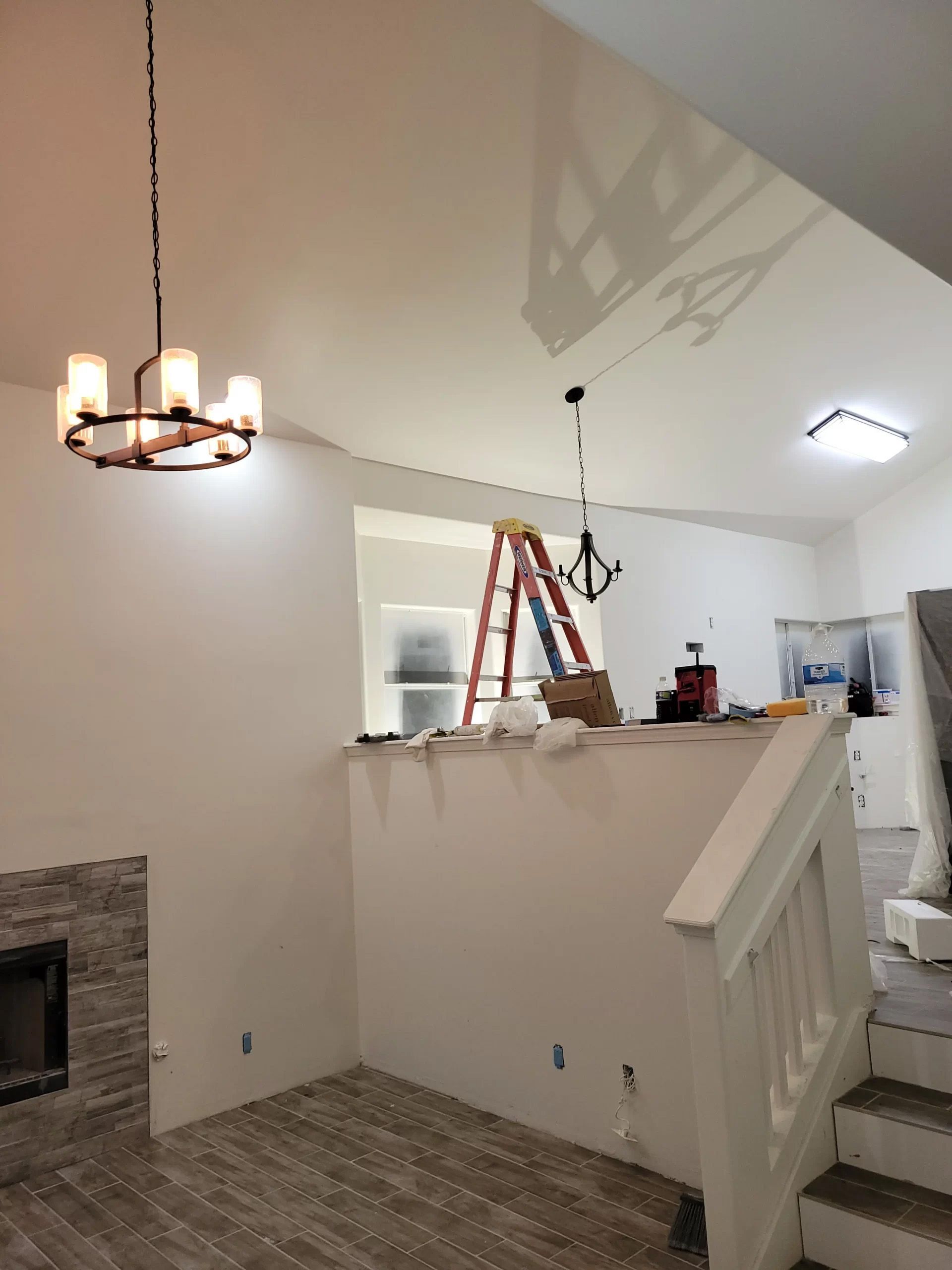 A living room with stairs and a chandelier hanging from the ceiling