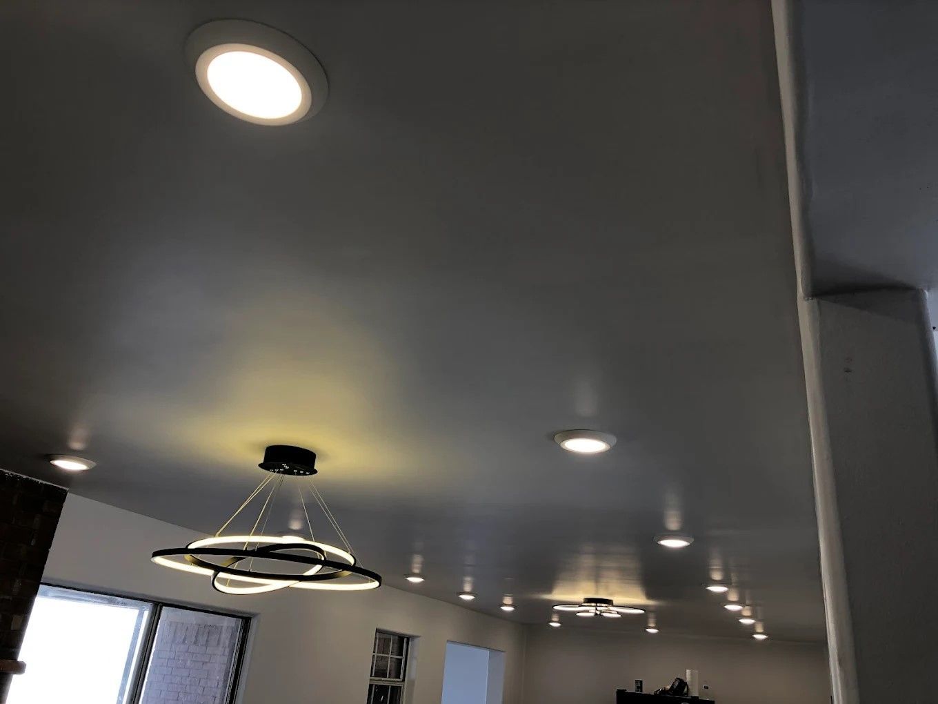 A person is using a drill to install a light switch on a wall.