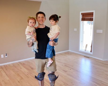 Image of a hardwood floor that is getting installed. You can see the entryway of a home with a wooden door and hardwood floor planks getting installed.