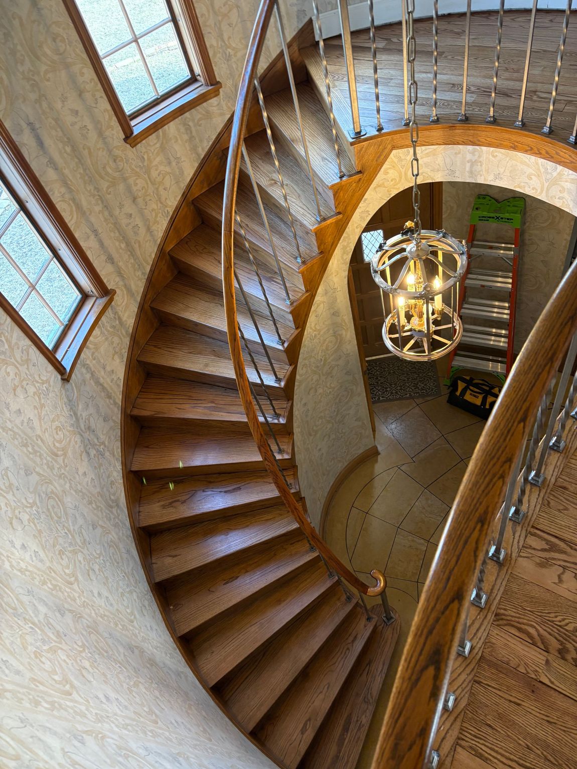 Picture of a wooden staircase with hardwood steps. You can see a spiral stair case leading up to a hardwood floor on the second floor of the house.