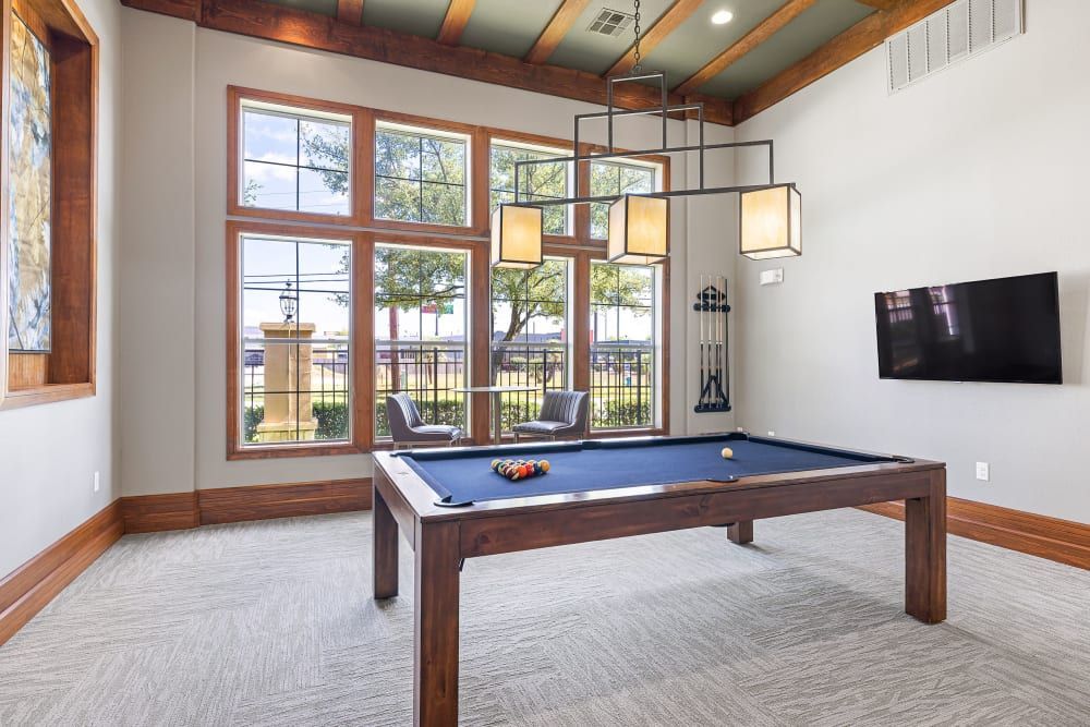 A pool table in the middle of the clubhouse entertainment lounge at Marquis at The Woodlands in Spring, TX.