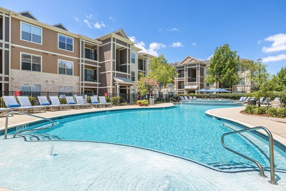 A large swimming pool in front of the apartment building at Marquis at The Woodlands in Spring, TX.