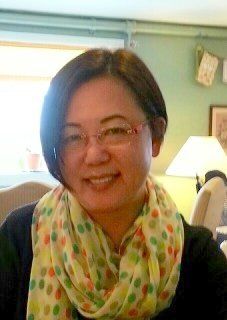 Woman with short dark hair and glasses smiles, wearing a colorful scarf.