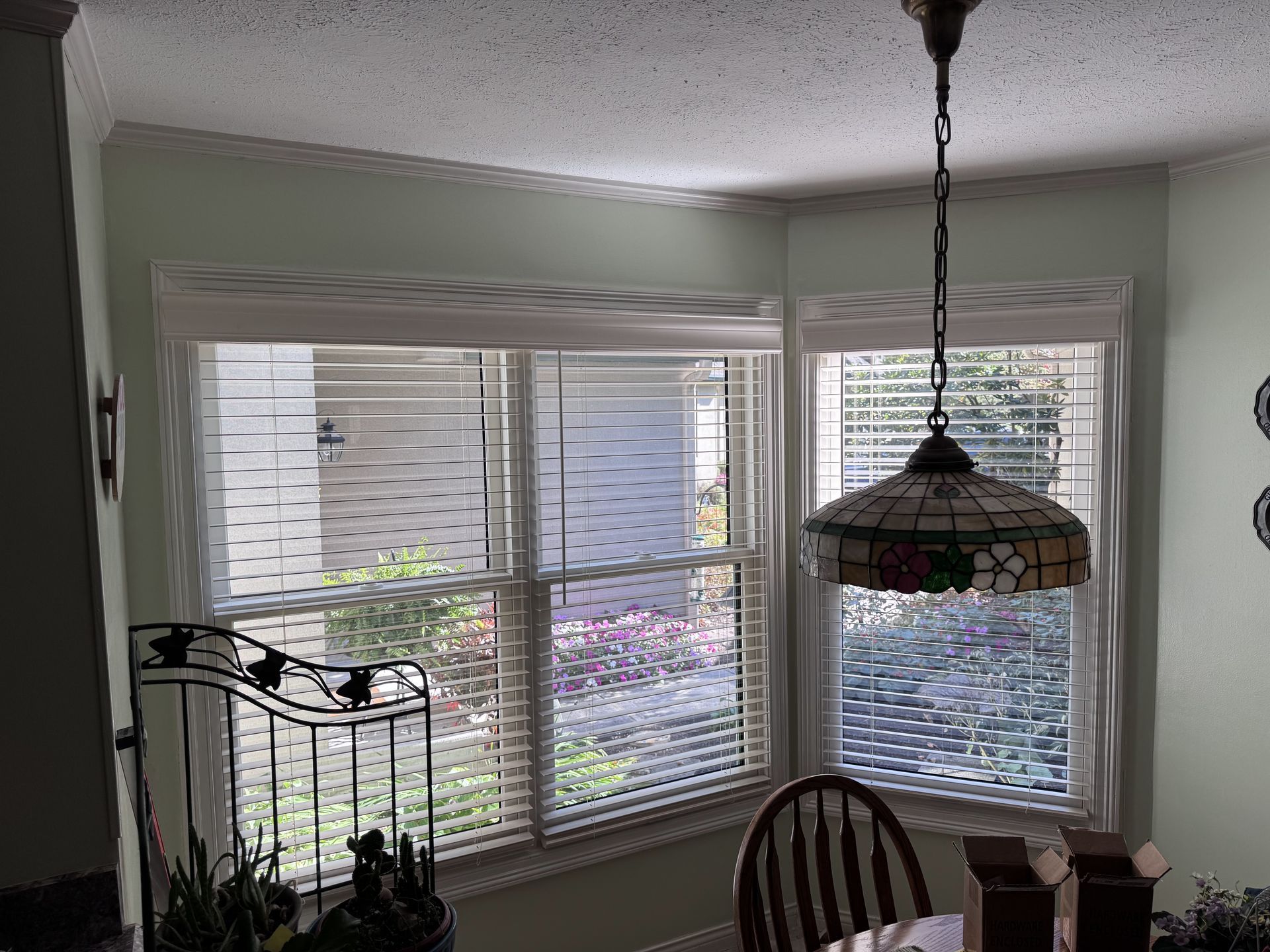 Dining area with windows, blinds, a pendant light, and a round table.