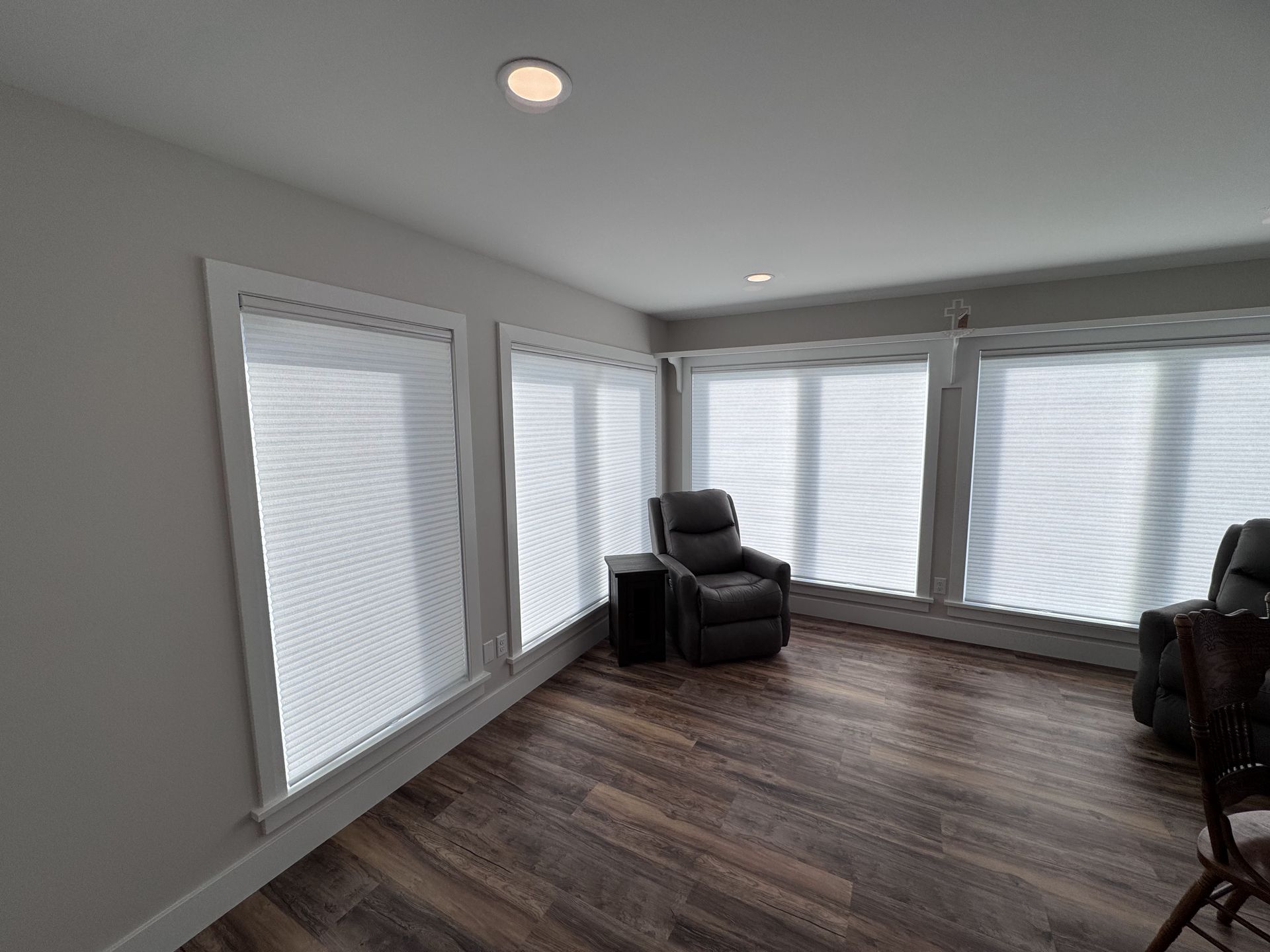Sunroom with shades, recliner chairs, and wood flooring.
