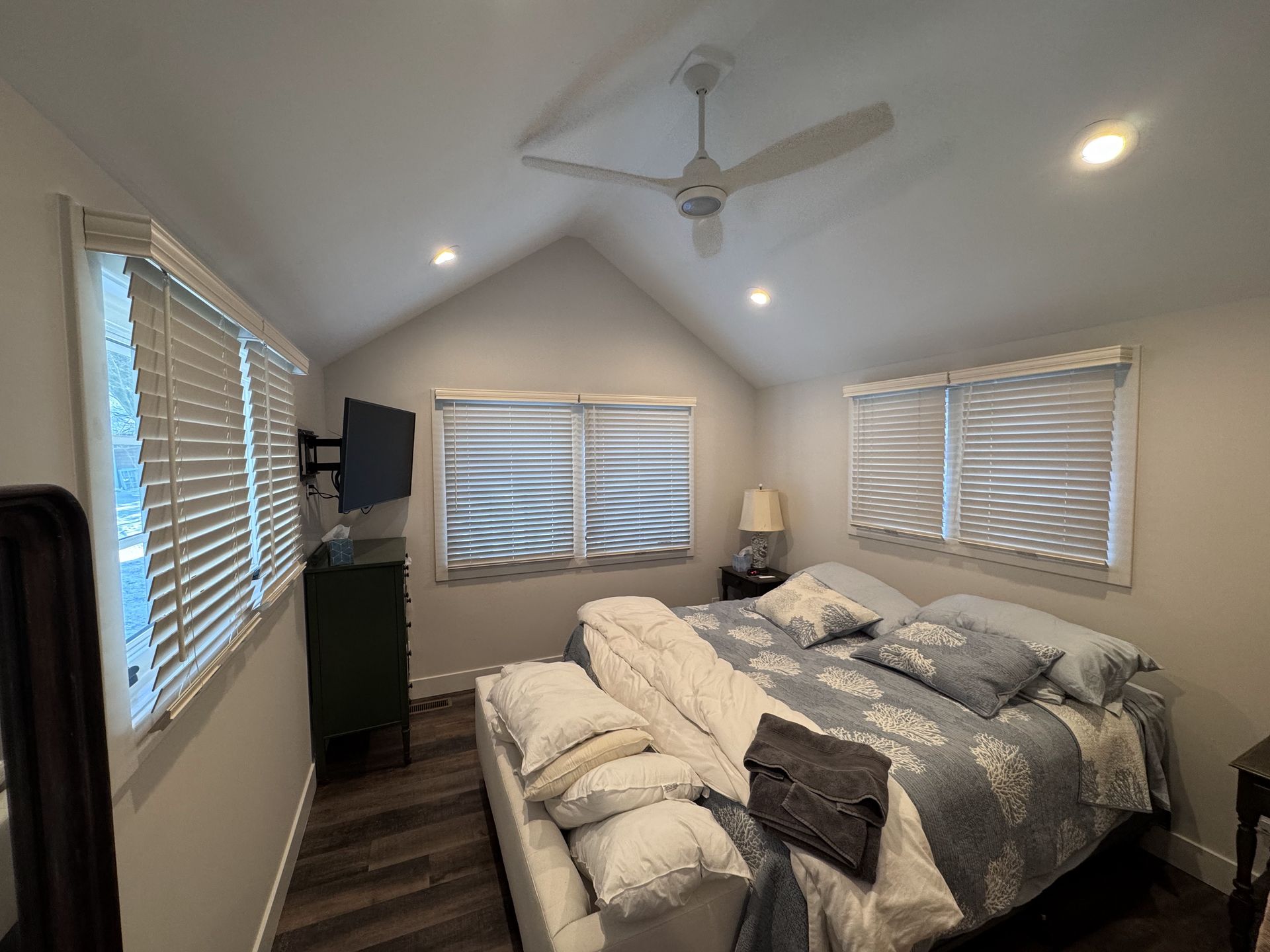 Bedroom with a bed, windows, TV, and a ceiling fan.