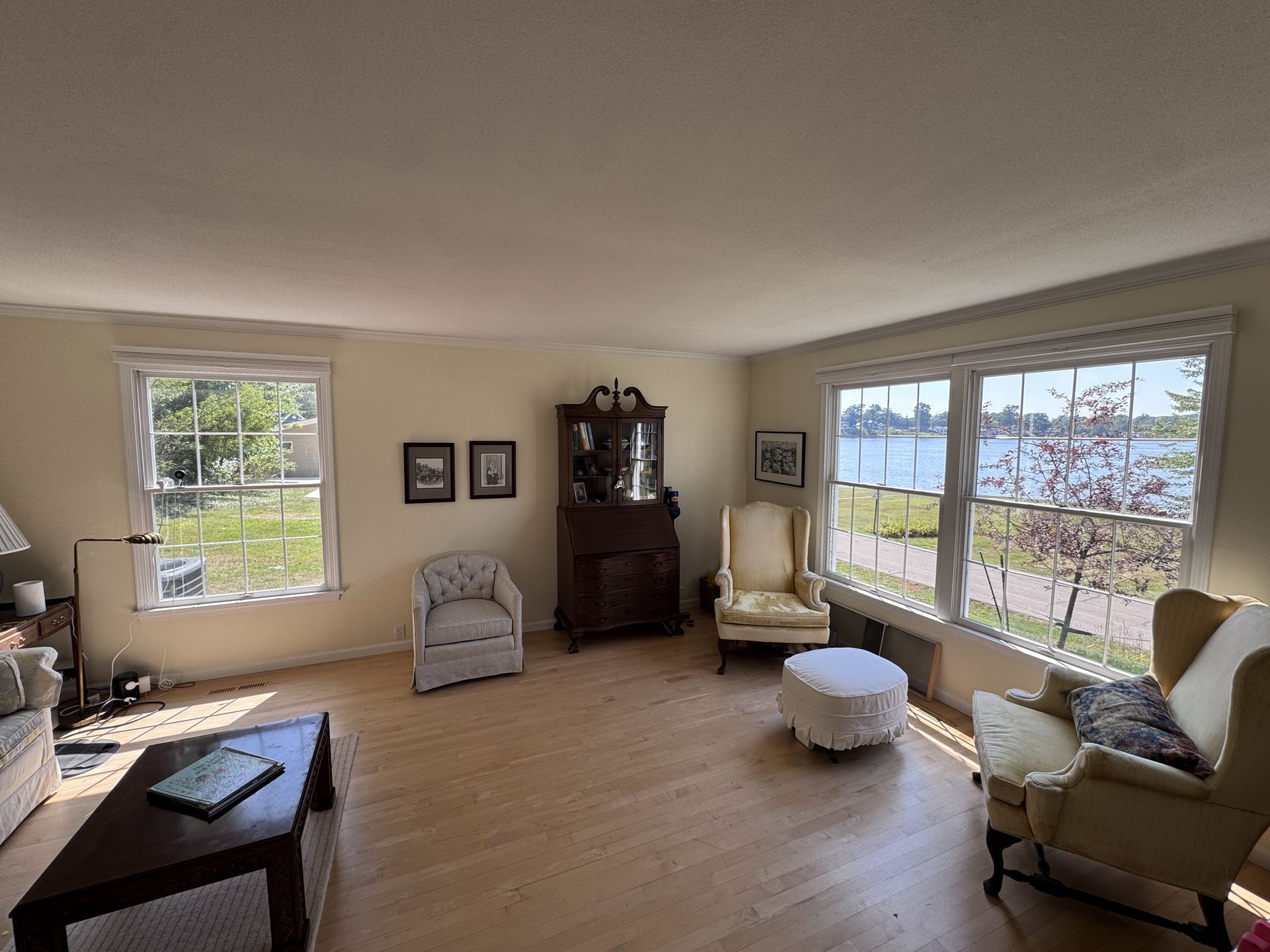 Living room with light wood floors, large windows, and antique furniture.