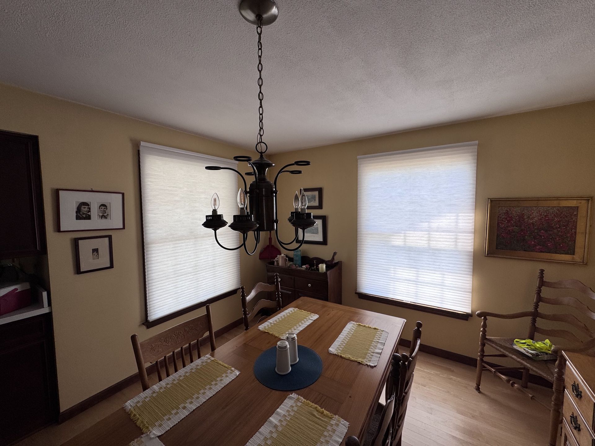 Dining room with table, chairs, and chandelier near two windows.