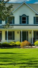 Two-story house with green shutters, white siding, and a large green lawn.