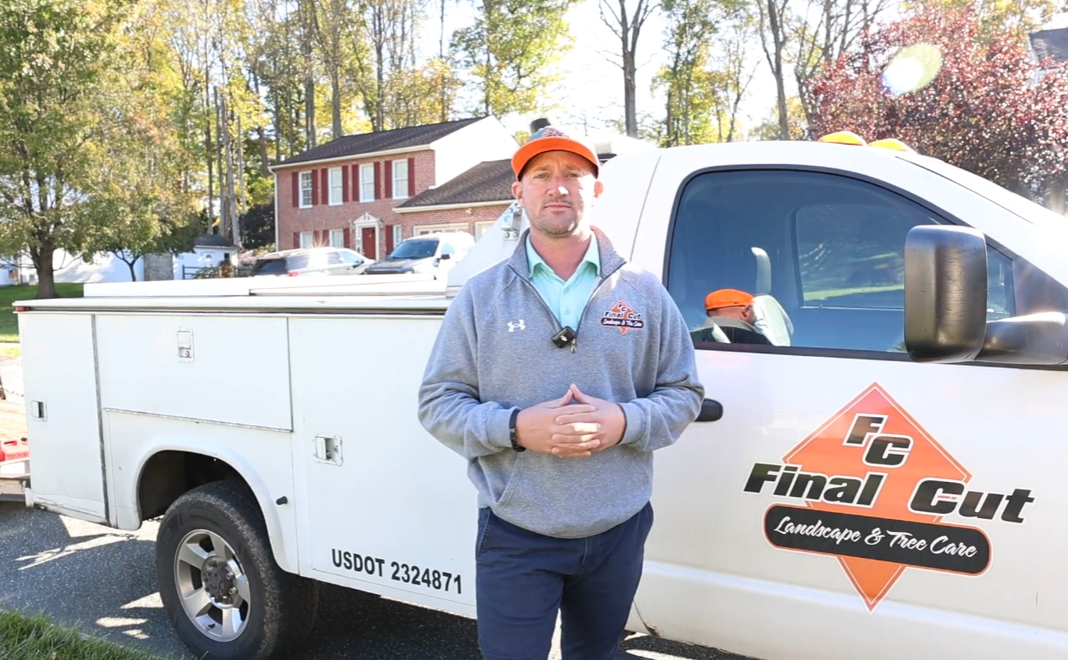 Man in orange cap standing by white truck with "Final Cut" logo; sunny day, house in background.