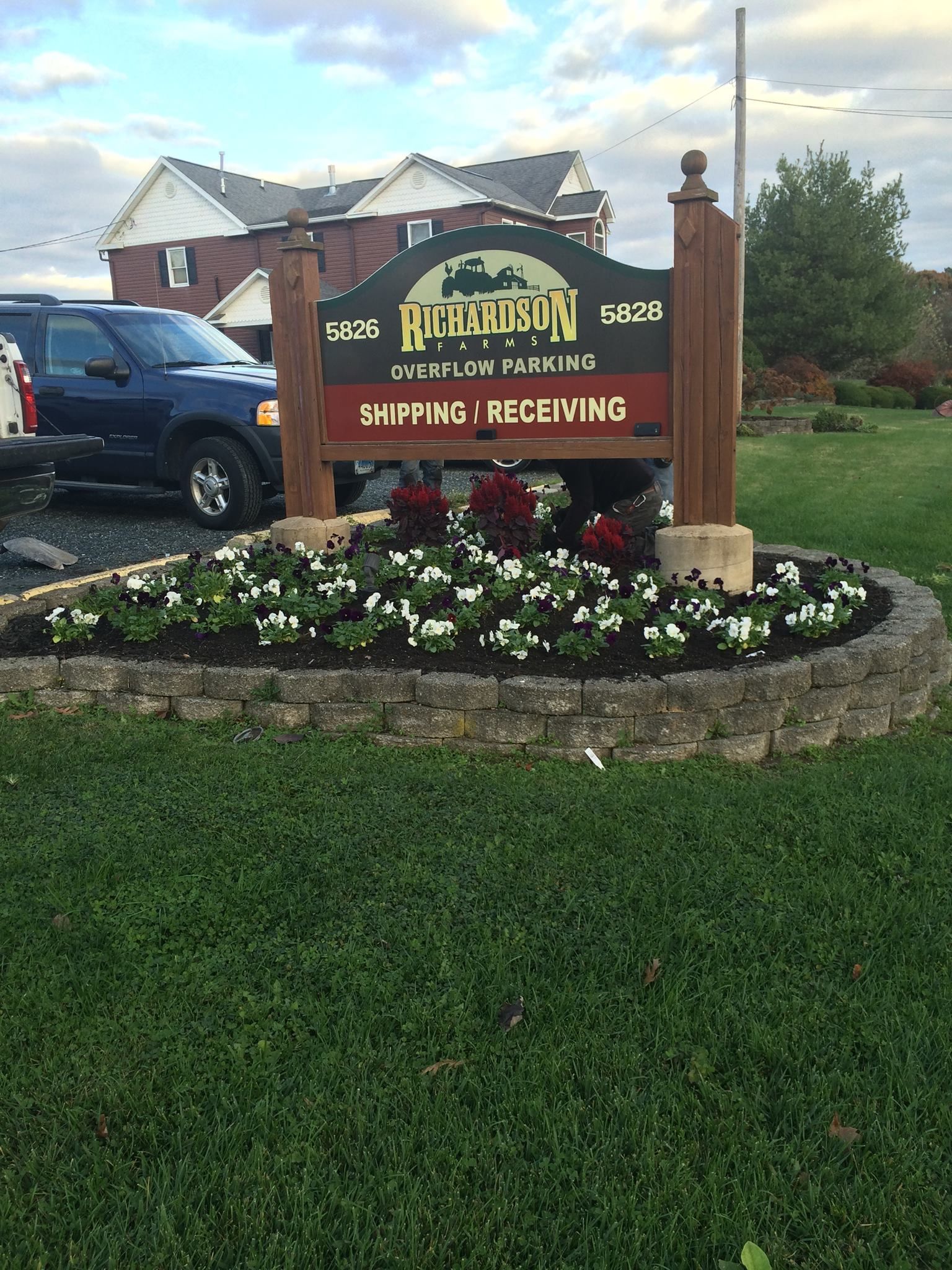 Sign for Post Falls, Idaho, with flowers and a blue truck.