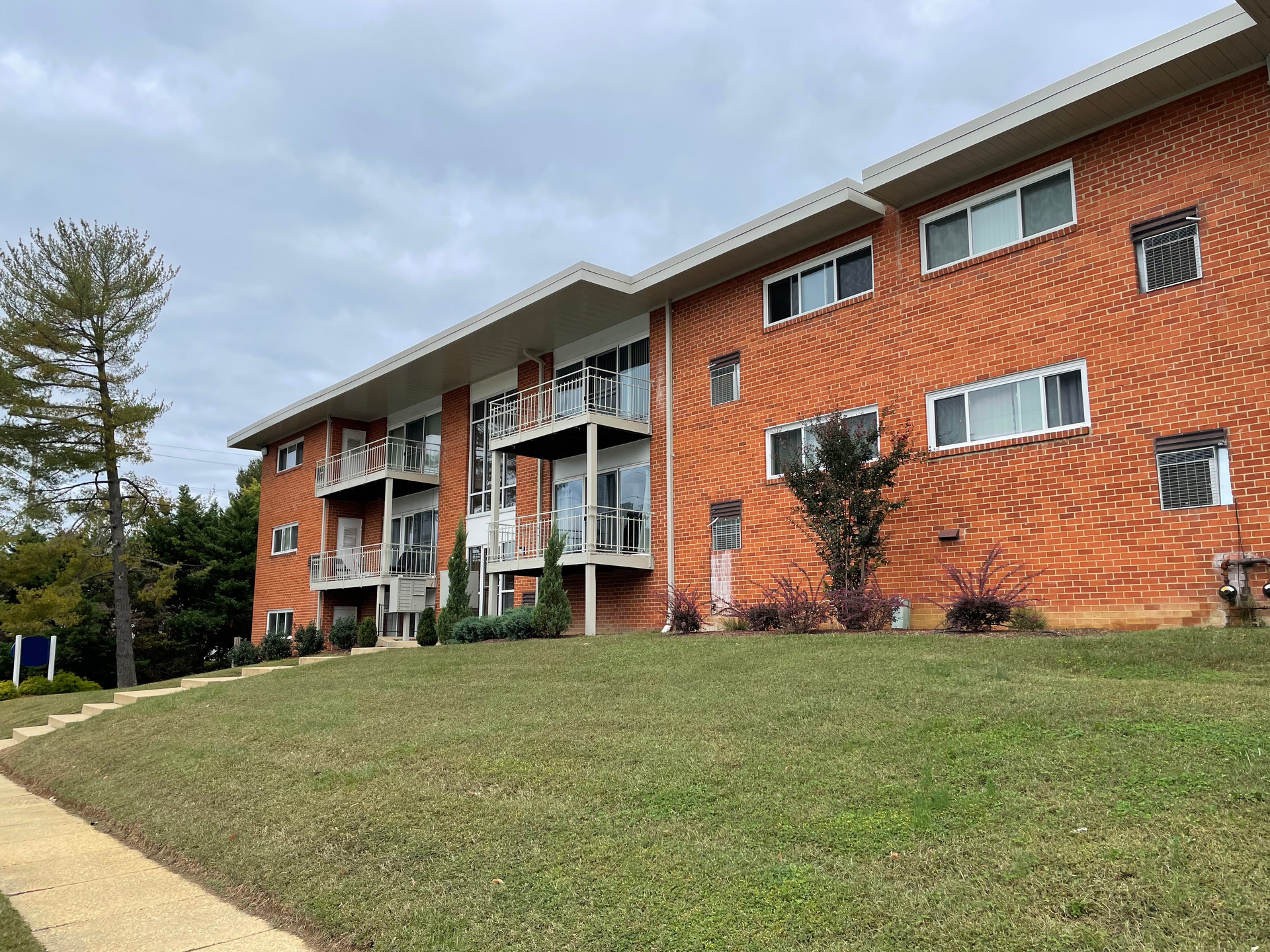 A large brick apartment building is sitting on top of a grassy hill.