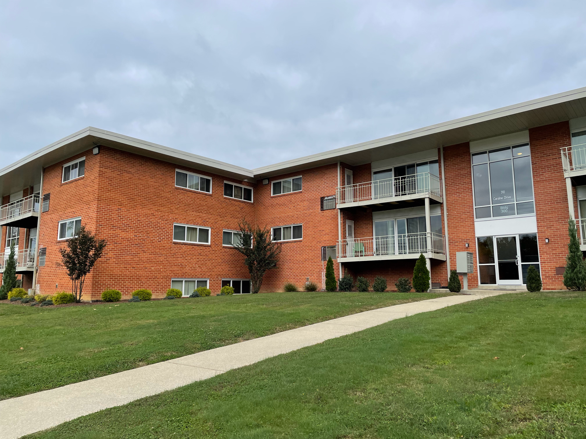 A large brick apartment building with a walkway leading to it.