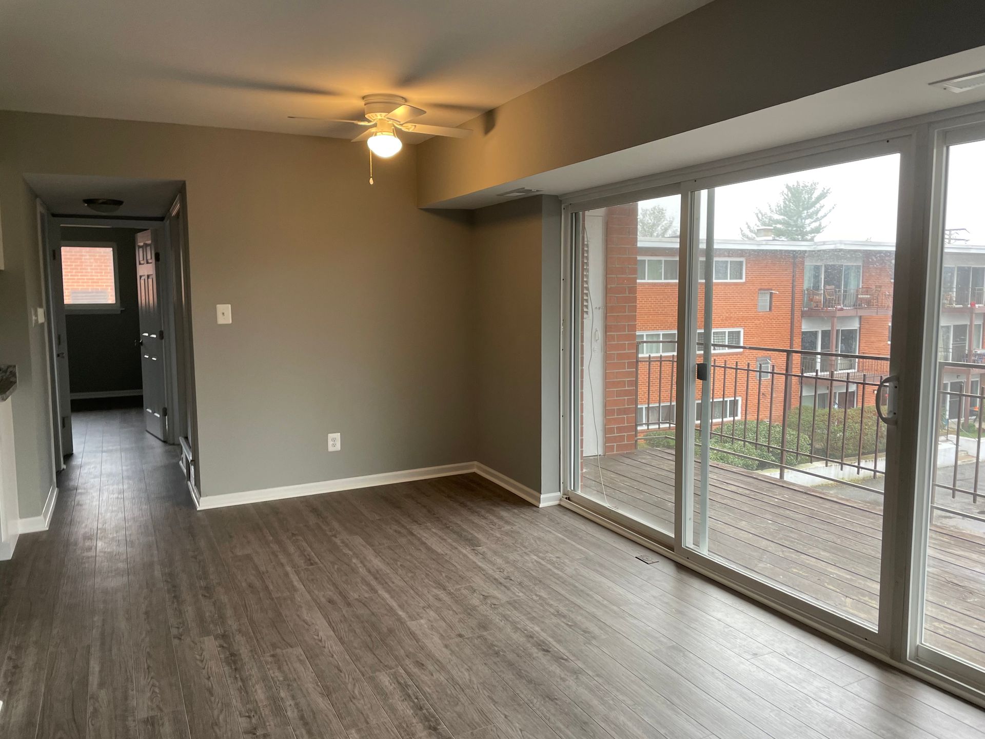 An empty living room with sliding glass doors and a ceiling fan.