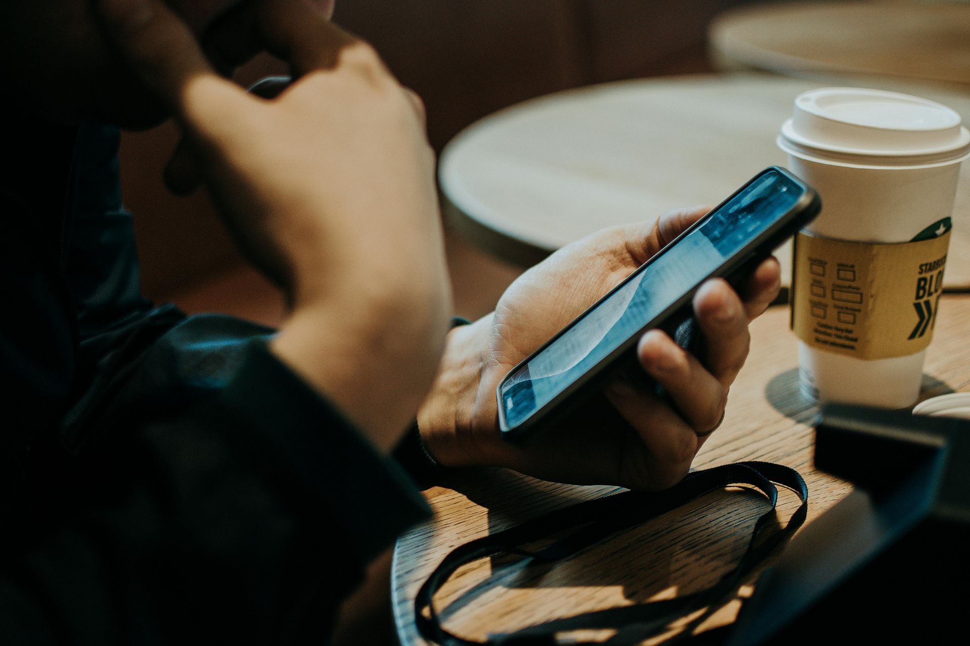 A person sitting in a café, browsing the web on their smartphone.