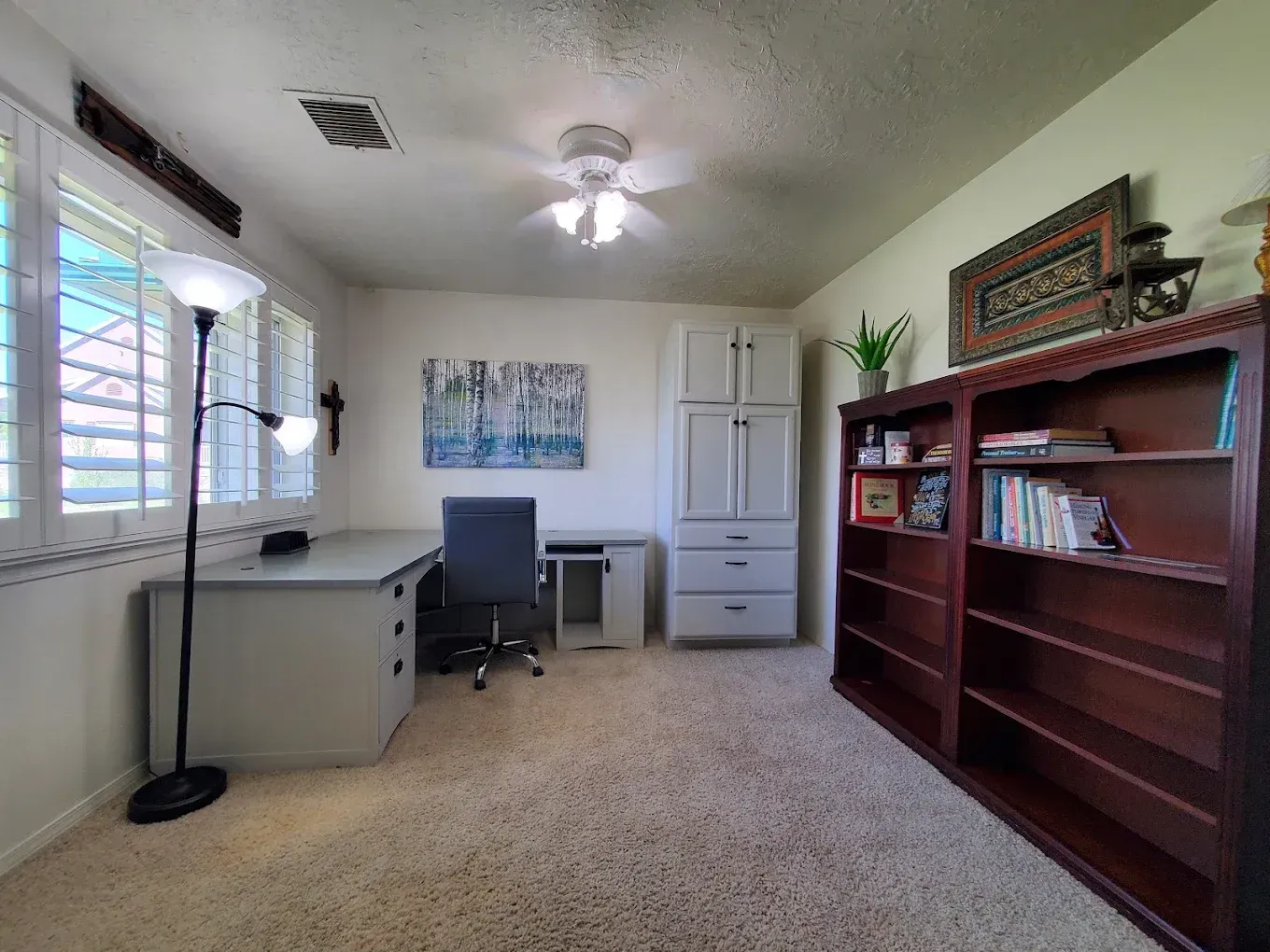 Home office with a desk, shelves, and a window with blinds.