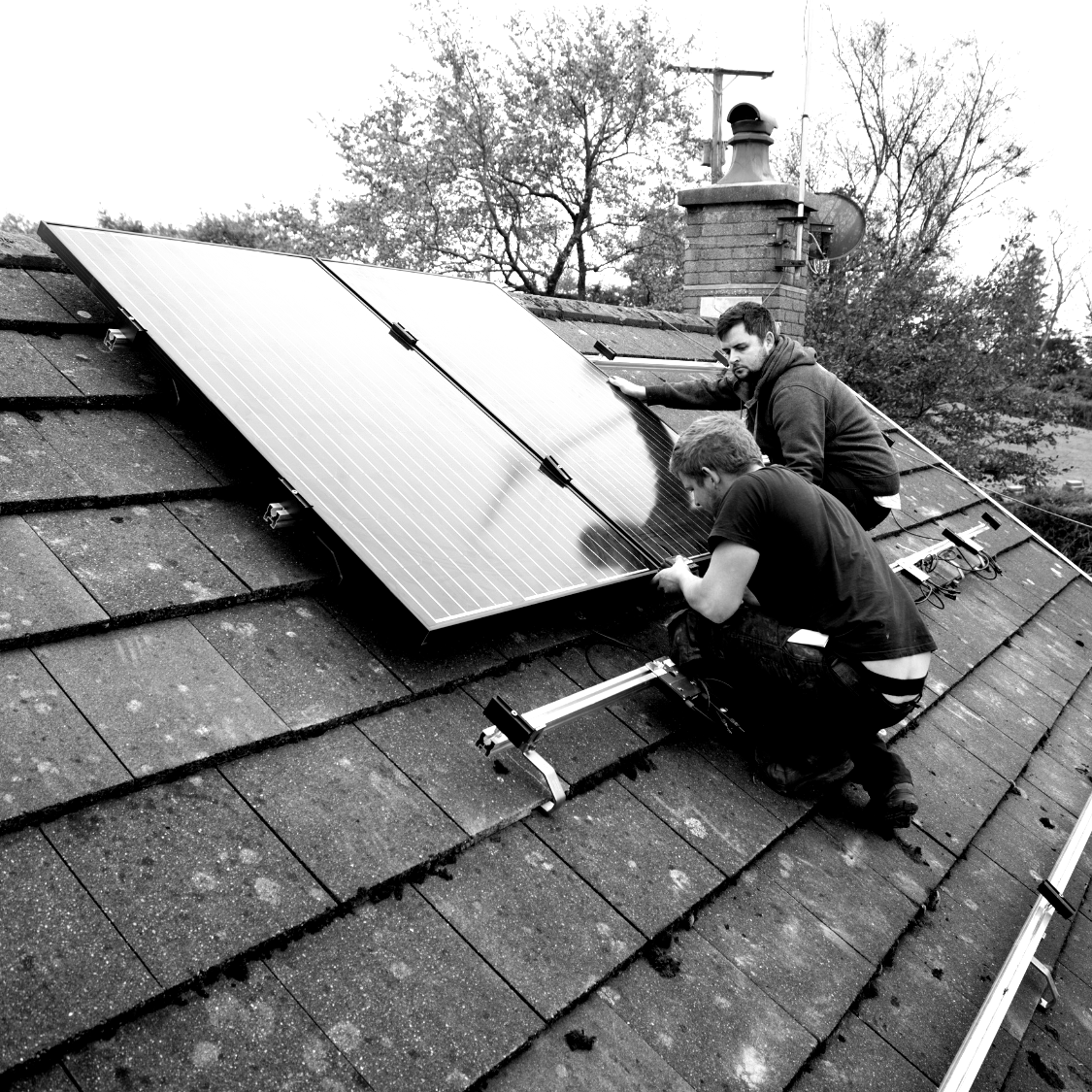 Two men are working on a solar panel on a roof.