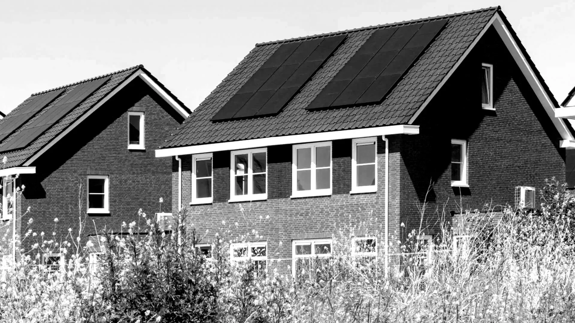 A black and white photo of a house with solar panels on the roof