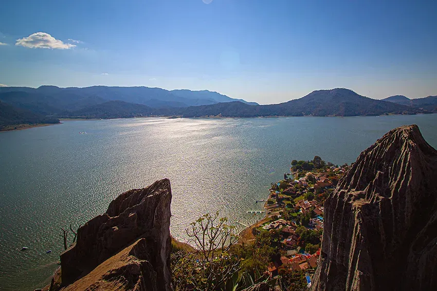 Una vista panorámica de un lago y montañas bajo un cielo azul, vista desde un afloramiento rocoso.
