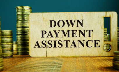 A wooden sign that says `` down payment assistance '' is surrounded by stacks of coins.