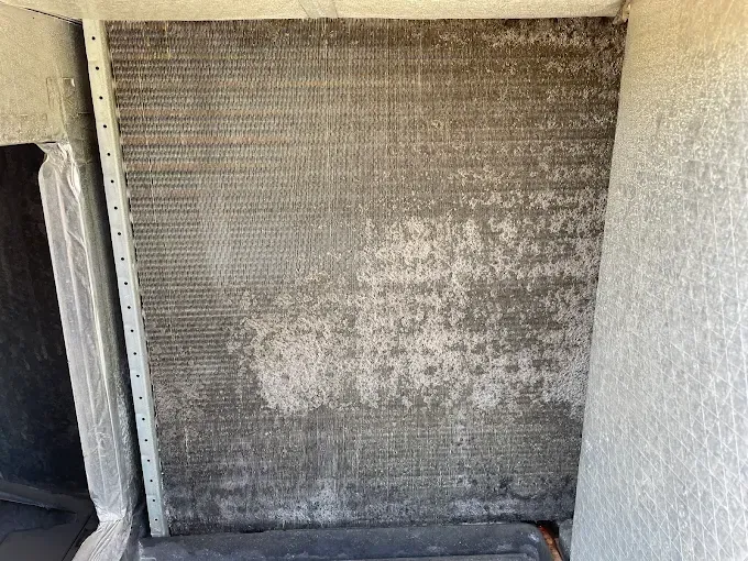 Dirty air conditioning unit coil in an outdoor setting, coated in dust and debris.