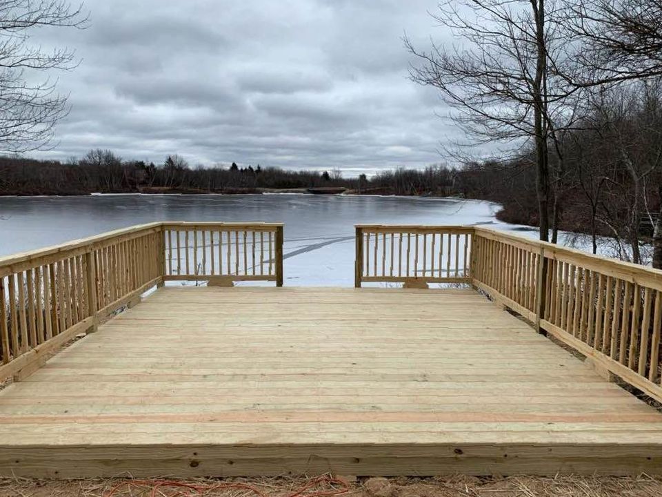 A wooden deck overlooking a lake on a cloudy day.