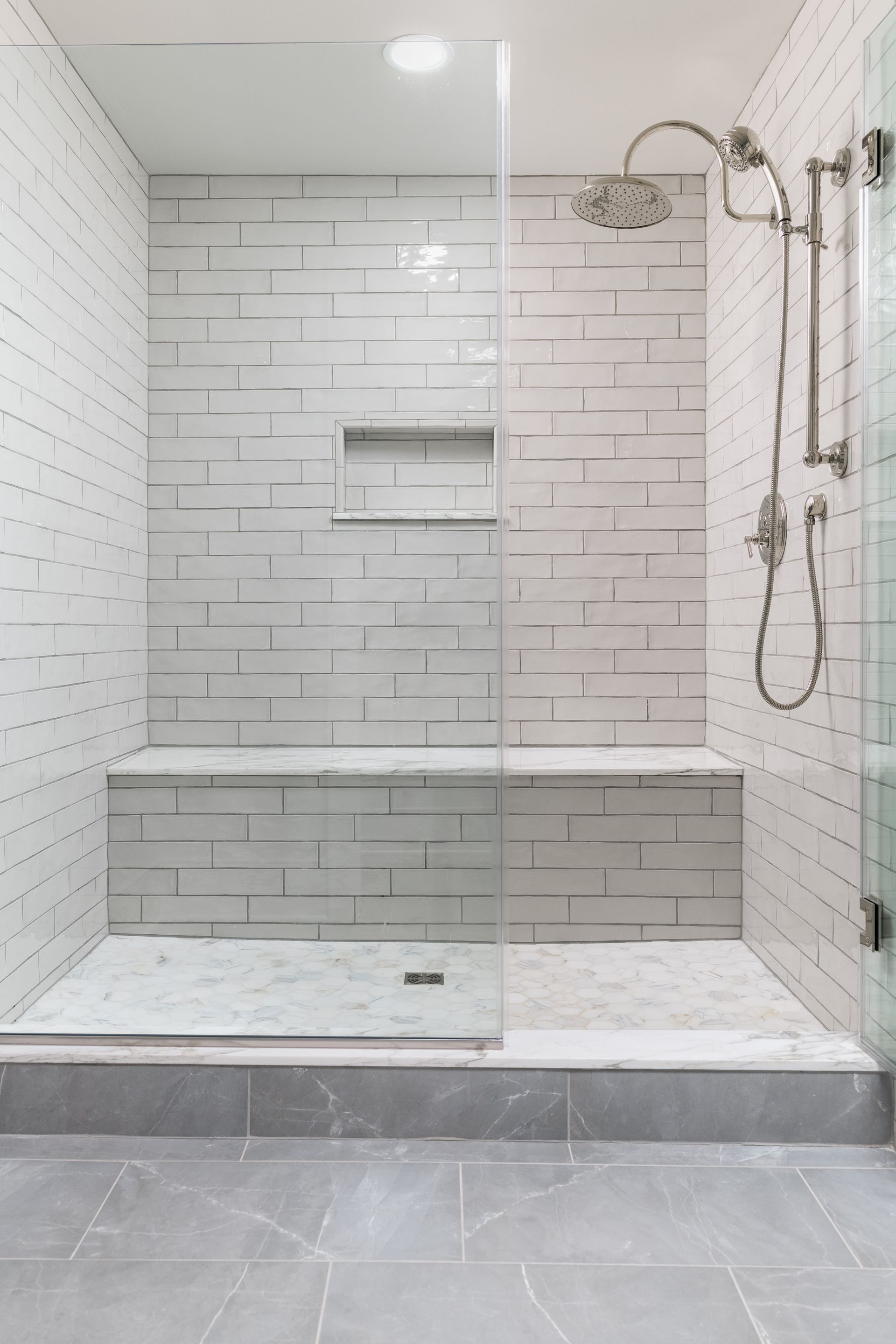 A bathroom with a walk in shower and a bench.