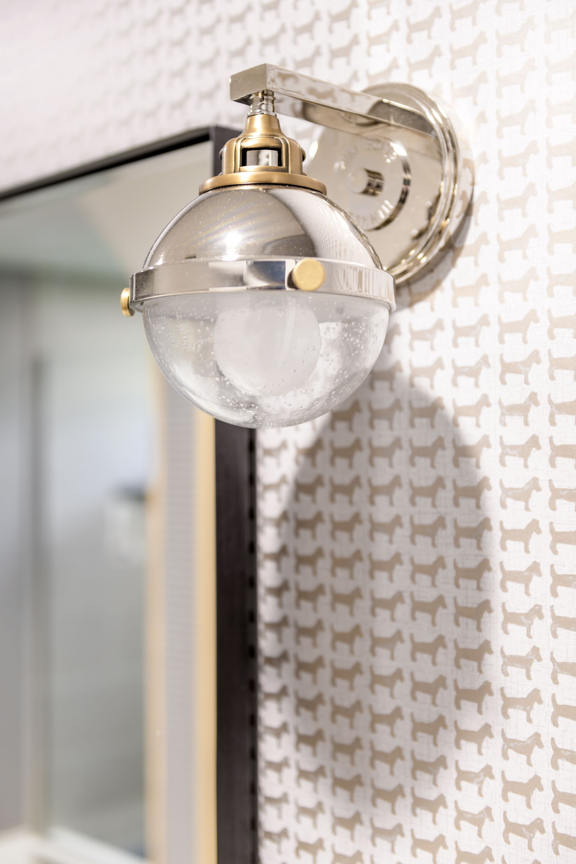 A bathroom with a mirror and a light on the wall.