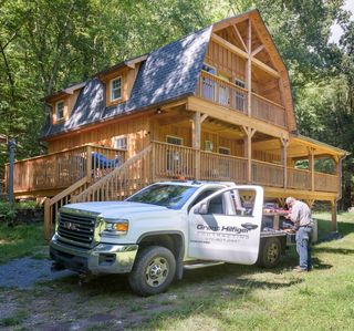 A white truck is parked in front of a wooden house