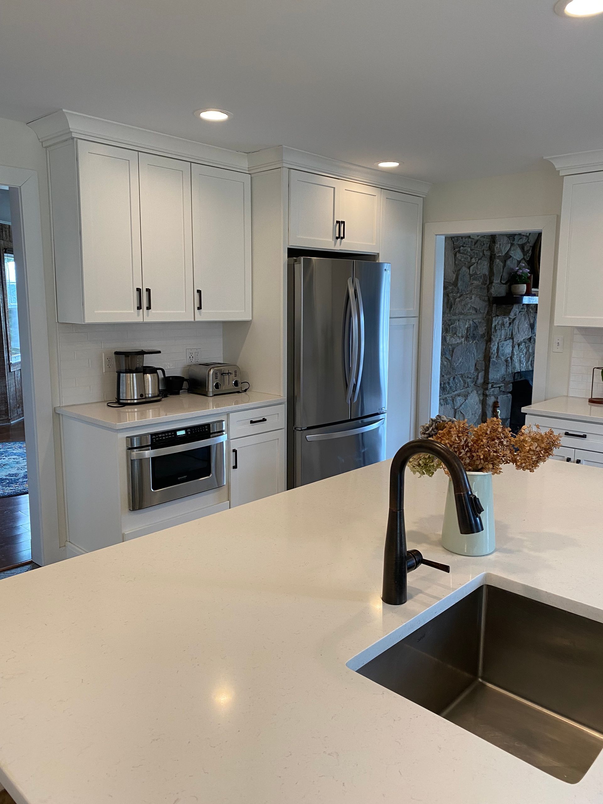 A kitchen with white cabinets , stainless steel appliances , a sink and a refrigerator.