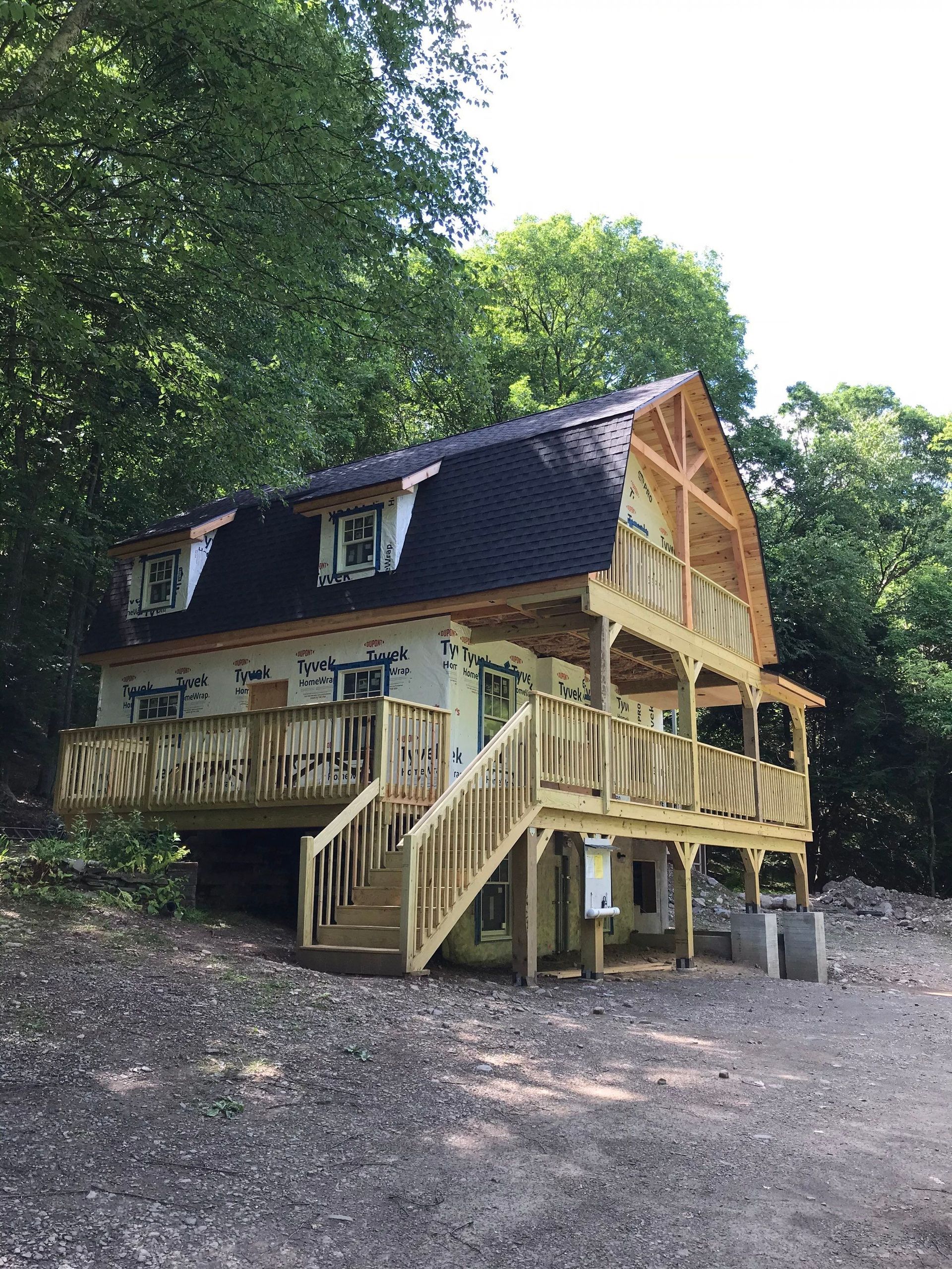 A large house with a large deck is surrounded by trees.