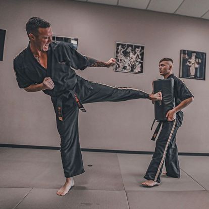 Two men are practicing martial arts in a gym.