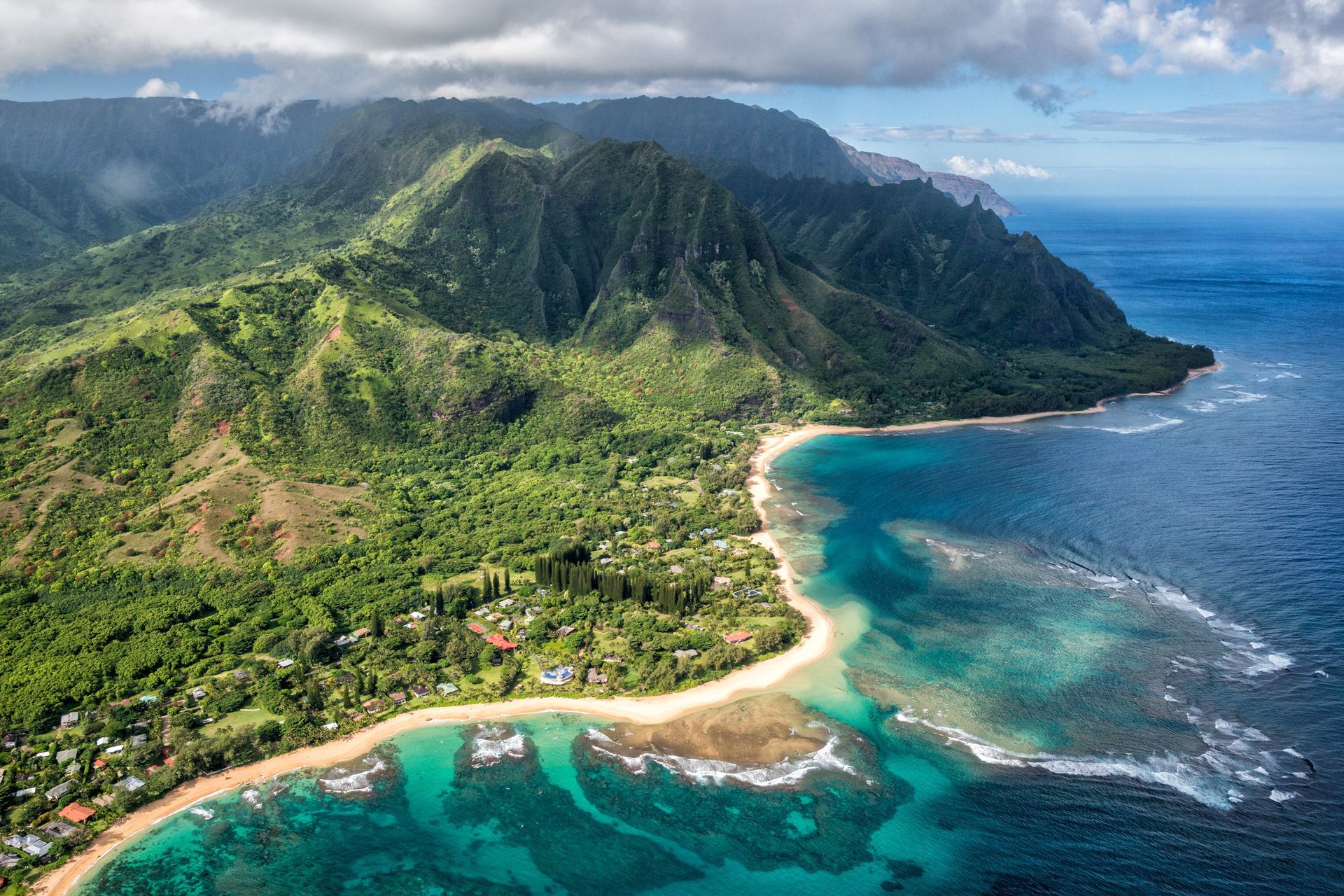 An aerial view of a tropical island with mountains and a beach.