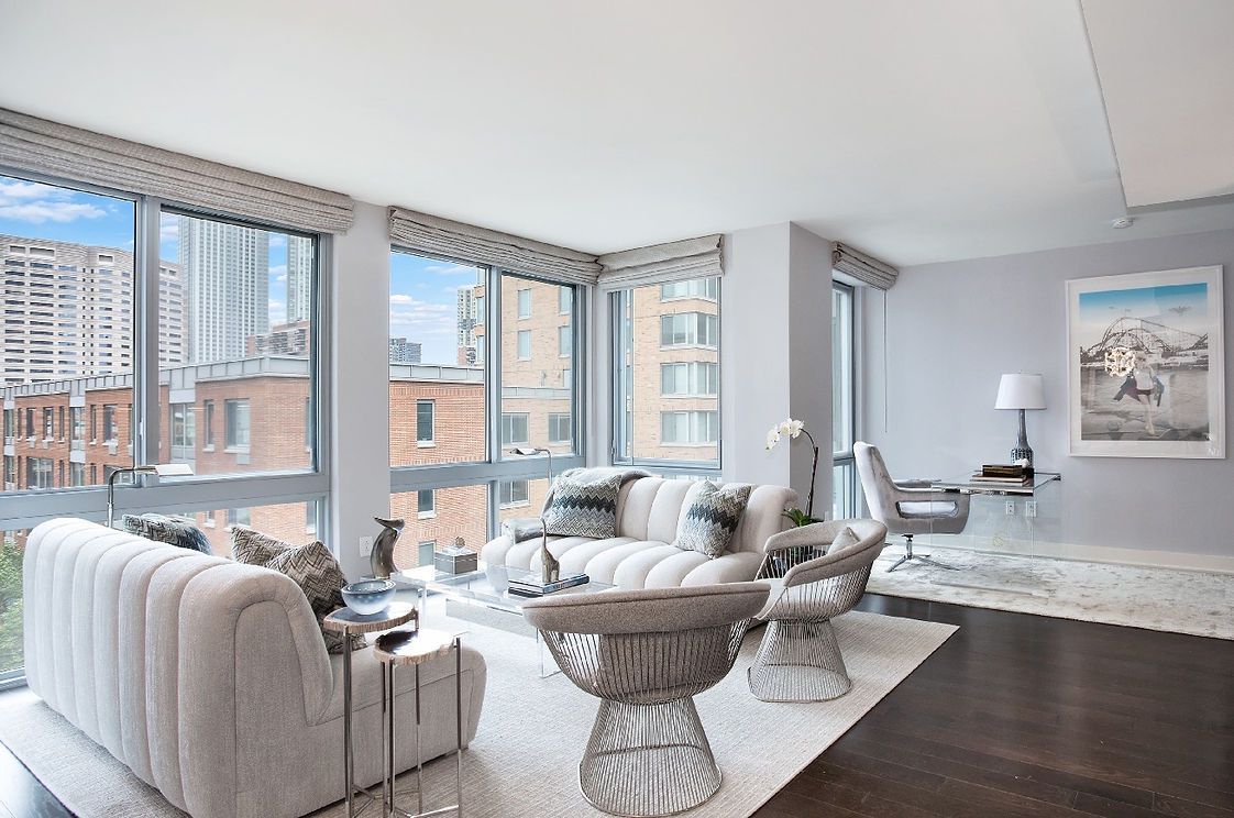 A living room with a couch , chairs , and lots of windows.