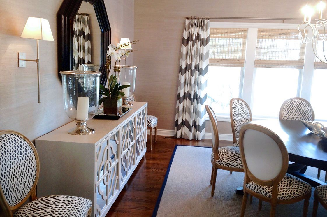 A dining room with a table and chairs and a mirror